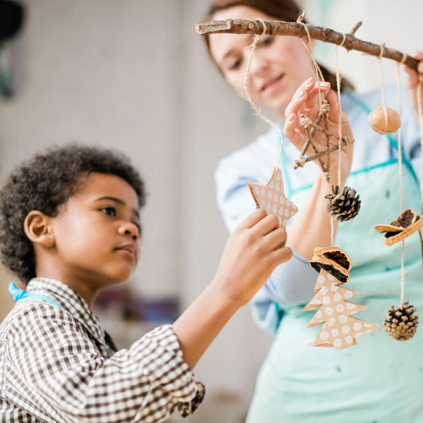 Teacher with elementary school student looking at wind chimes with natural elements