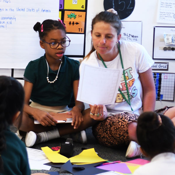 Teacher sitting on the floor with middle school students