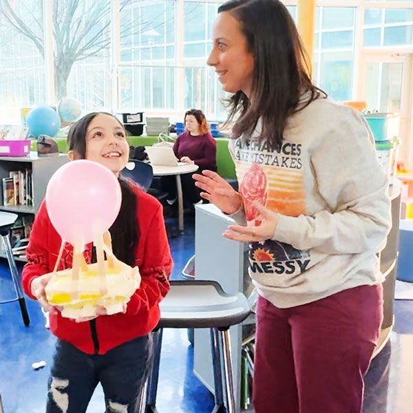 Teacher next to a girl with a balloon engineering project