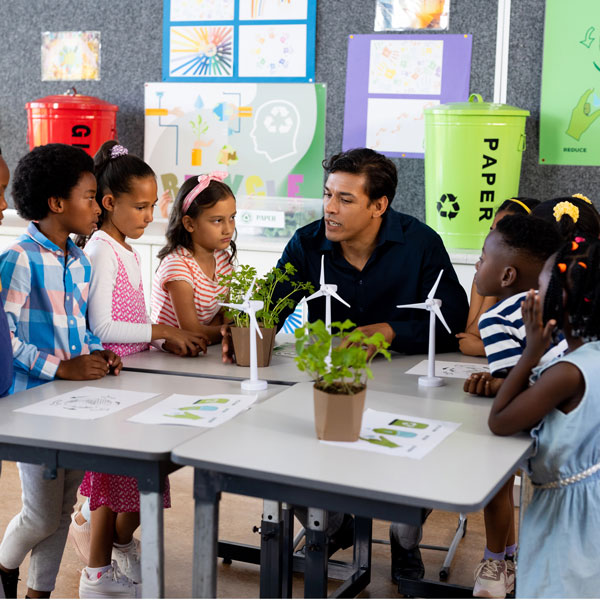 teacher at student desks guiding a project on wind power