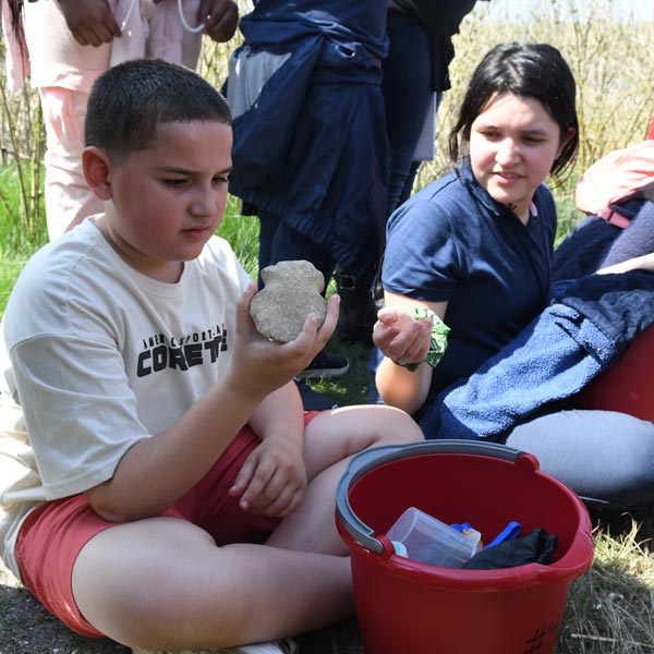 A boy and girl on a field trip looking at a stone