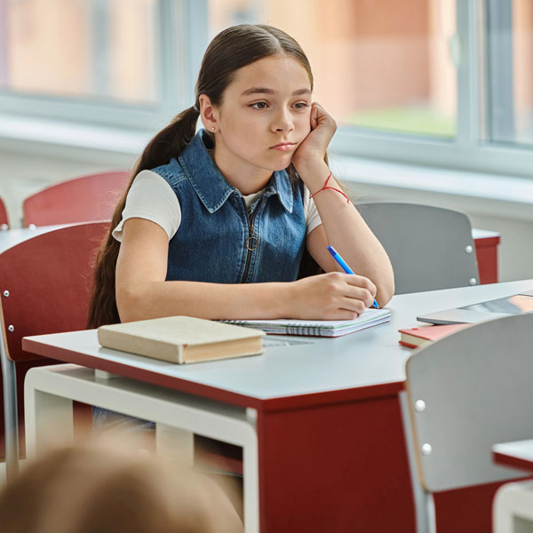 A bored school girl sitting at her desk in calss