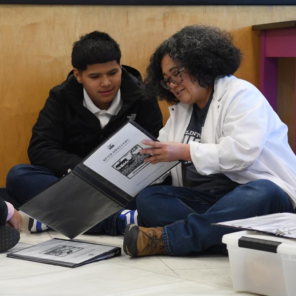 Teacher sitting on the floor with a middle school student